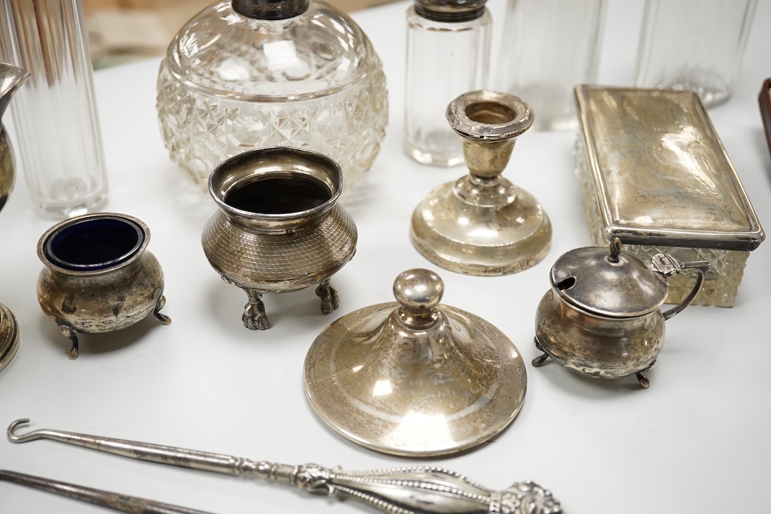 An early 20th century silver mounted cut glass scent bottle, five silver mounted glass toilet jars, a pair of silver mounted dwarf candlesticks, two silver condiments, a sterling jug(weighted), a sterling cup and cover(w